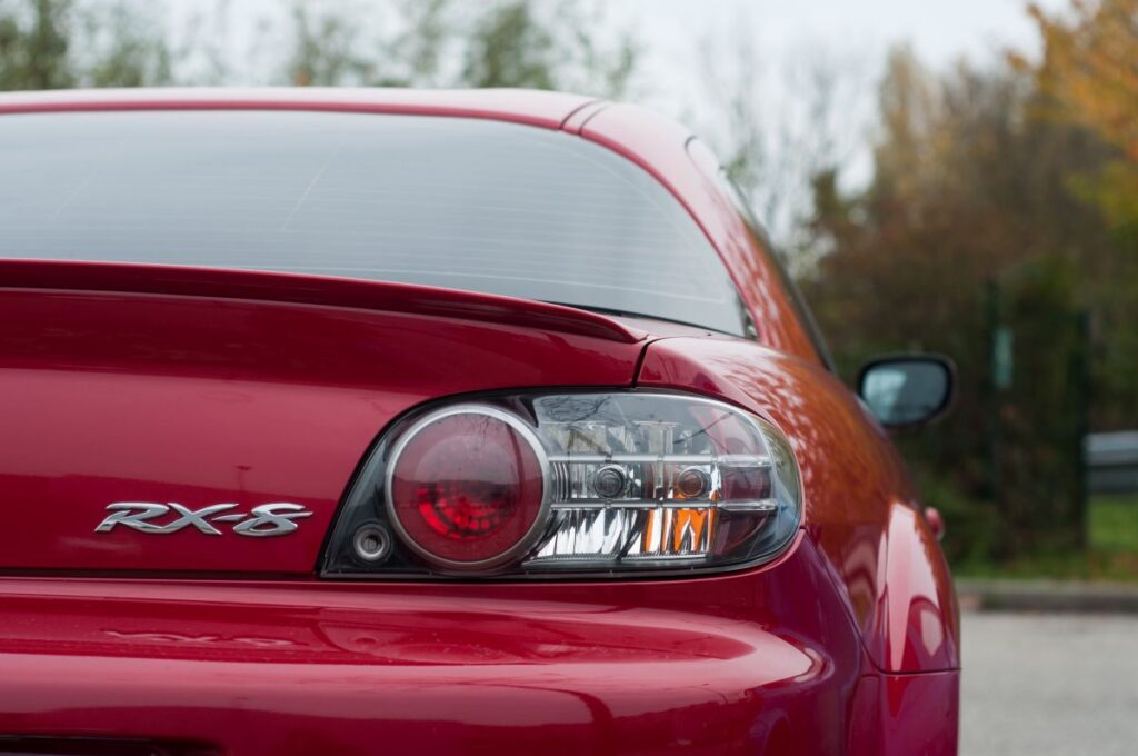 Closeup of rear light and sign on red Mazda RX 8 parked in the street