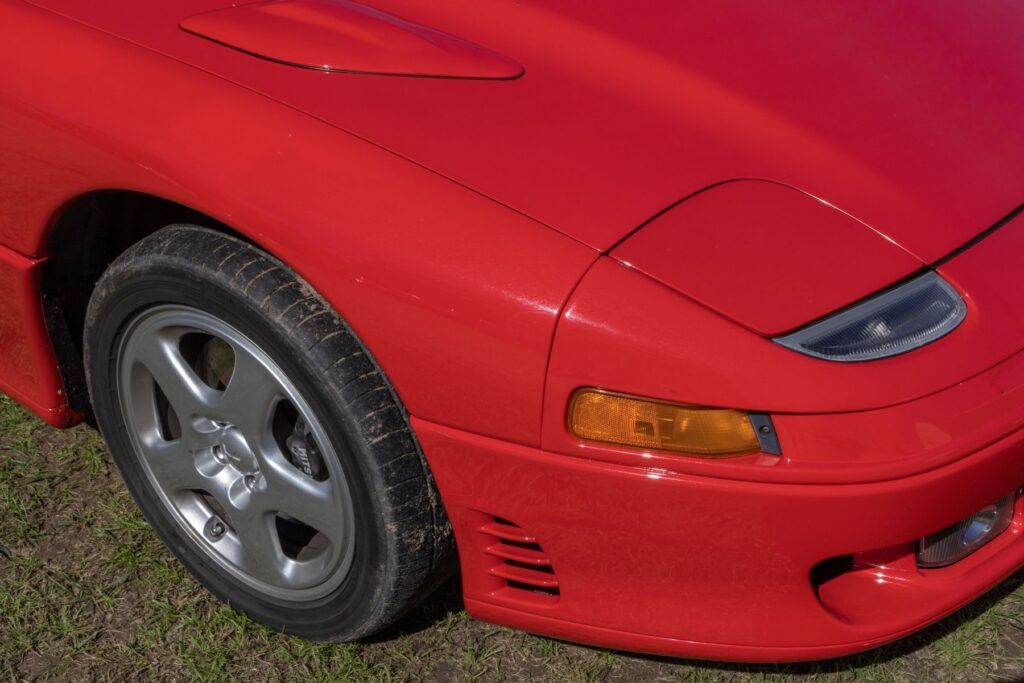 Red Mitsubishi 3000GT VR4 showing front bumper, headlight and wheel