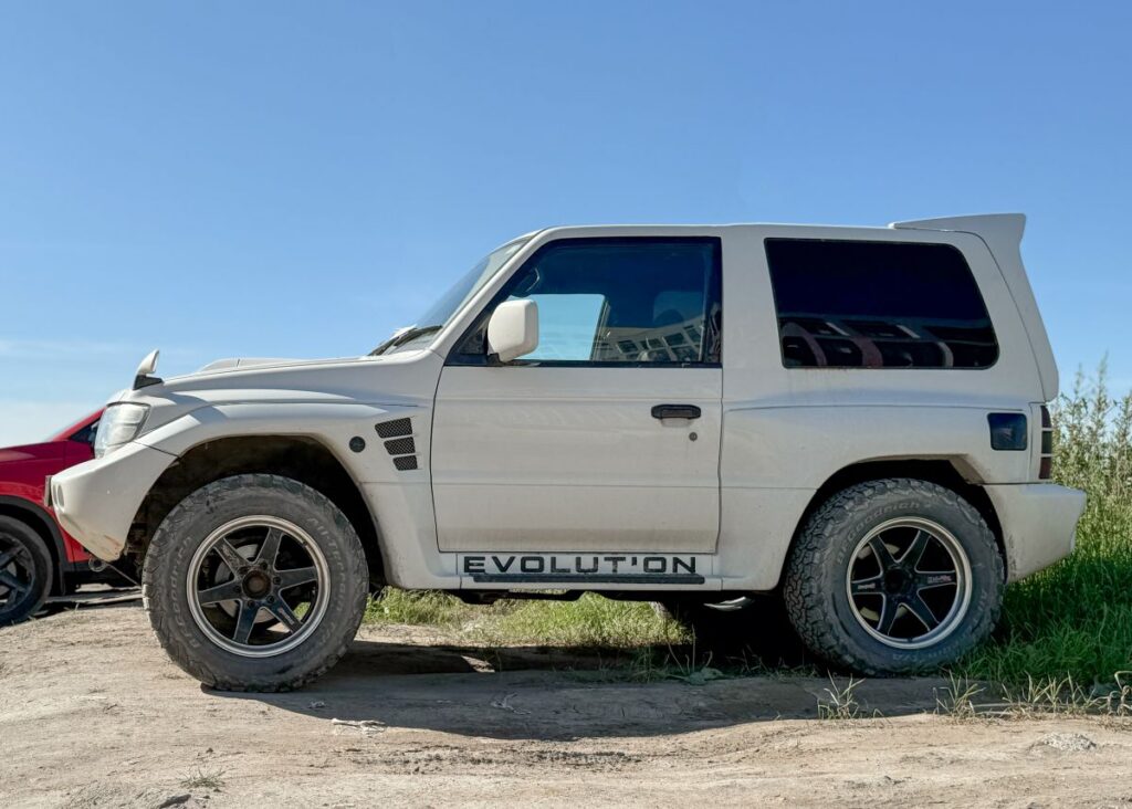 A white Japanese SUV car Mitsubishi Pajero Evolution parked on street