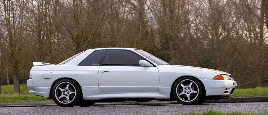 1993 white Nissan Skyline classic car driving on a British road