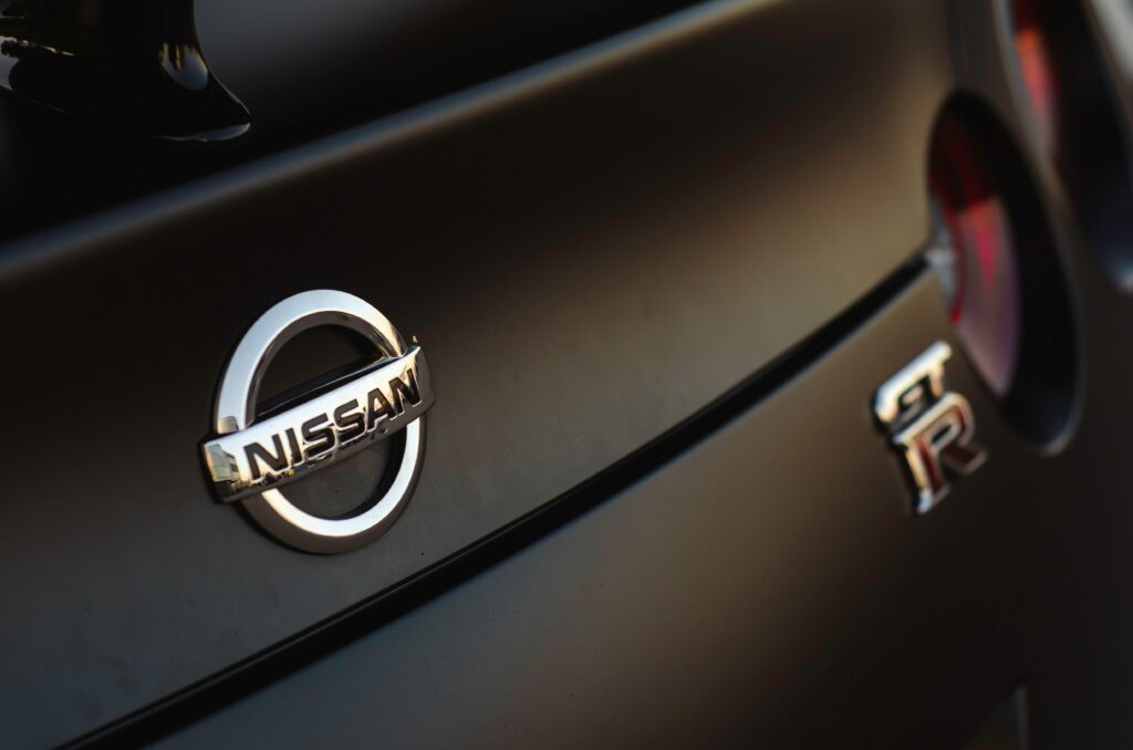 Close-up on the Nissan logo on the back of a car with the GT-R logo out of focus