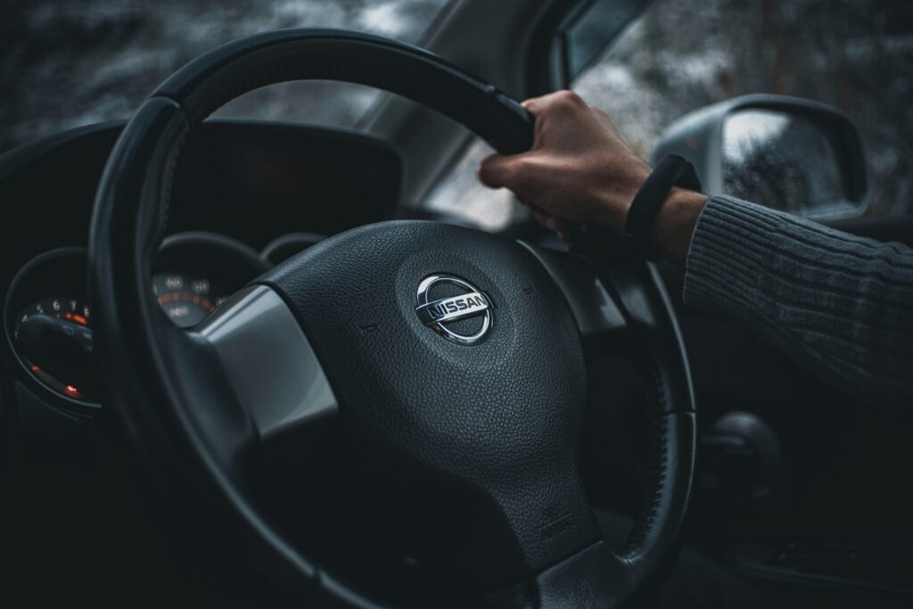 Nissan steering wheel close up with a hand gripping the wheel